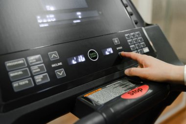 Koşmaya hazır olun. Ev spor salonundaki koşu bandındaki yeşil düğmeye basar. Koşu bandındaki dur düğmesine basar.