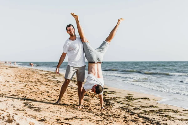 best friends cuddling on the beach,vacation with a friend at sea,fooling around with a friend,friend holds friend in his arms,walk along the beach,two nice guys,nice and lovely guys