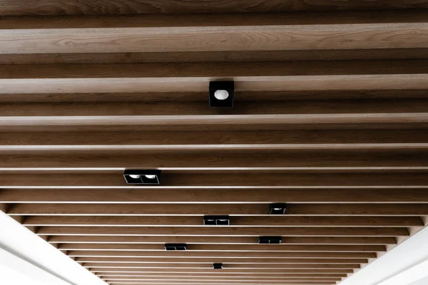 木製パネル付きの創造的な天井 現代的な木製の吊り下げ天井 天井の黒いロフトライト 省エネ電球 — ストック写真