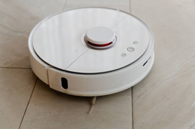 Temizlik sırasında robot elektrikli süpürge, beyaz robot elektrik süpürgesi döküntüleri temizliyor, elektrikli süpürge ile ev temizliği, elektrikli süpürge, elektrikli robot temizleme teknolojisi.