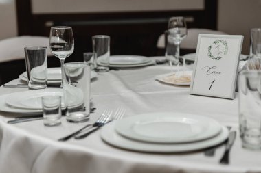 Düğün salonundaki düğün dekorasyonu, düğün süslemeleri ile süslenmiş düğün masası, balayı masası, masadaki tatil yemekleri, düğün masasındaki koltuklar.