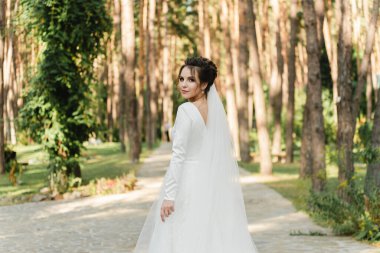 Şirin gelin güzel bir gelinlik içinde bir buket tutuyor, güzel gelin arkası dönük duruyor