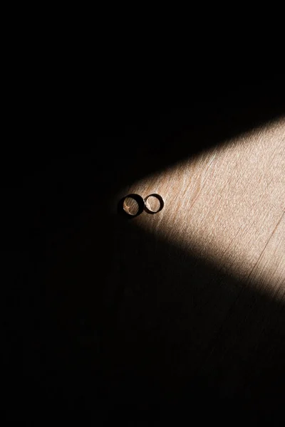 光は二つの結婚指輪と暗い背景の周りに落ち結婚式の指輪ホワイトゴールドブライダルジュエリー結婚式の指輪 — ストック写真