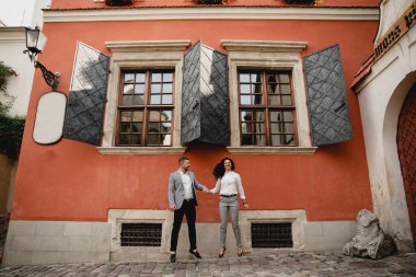 Orta yaşlı, birbirine aşık bir çift güzel, kırmızı, yaşlı bir evin arka planında el ele tutuşuyorlar. Gençler neşe içinde zıplıyorlar. Birbirlerine aşık çiftler evin yanında zıplıyorlar.