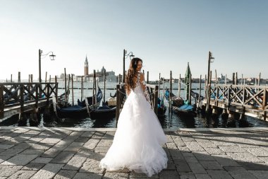 Gelinlik giymiş güzel bir gelin ve iskelenin yanında duruyor. Şık bir gelinlik, gülümseyen bir gelin.,