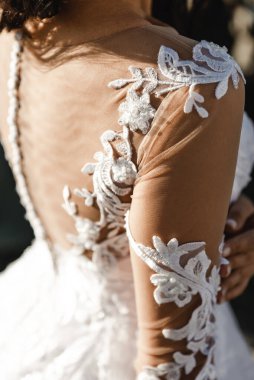 Gelinin sırtında gelinlik, arkasında düğmeler olan gelinlik, beyaz bir gelinliğin güzel süsü.