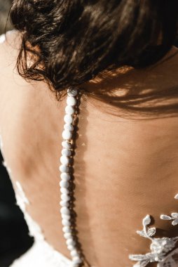 Gelinin sırtında gelinlik, arkasında düğmeler olan gelinlik, beyaz bir gelinliğin güzel süsü.