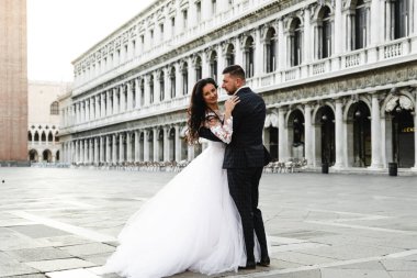 Damat geline, damada şık bir ekose takım elbise, orta yaşlı gelin, şık bir gelinlik, Avrupalı bir gelinin düğün günü ve Gürcü görünümlü bir damada sarılır.