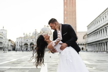 Damat geline, damada şık bir ekose takım elbise, orta yaşlı gelin, şık bir gelinlik, Avrupalı bir gelinin düğün günü ve Gürcü görünümlü bir damada sarılır.