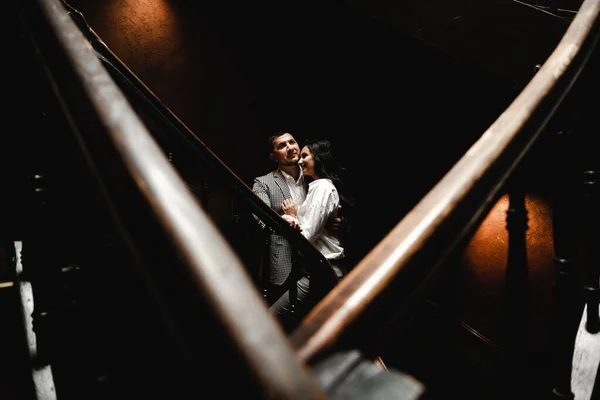 一对夫妇站在楼梯上的阴凉处 一对夫妇站在黑暗的背景上 那里的光线从上面射出 — 图库照片