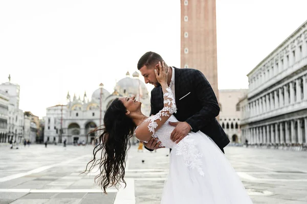 Damat geline, damada şık bir ekose takım elbise, orta yaşlı gelin, şık bir gelinlik, Avrupalı bir gelinin düğün günü ve Gürcü görünümlü bir damada sarılır.