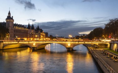 Paris 'te alacakaranlıkta taş köprü Pont au Change. Solda Conciergerie kuleleri var, Seine nehrinin kuzey kıyısında.