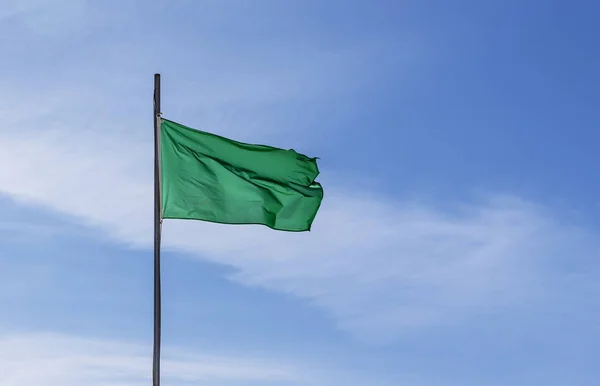 Green flag waiving against the sky