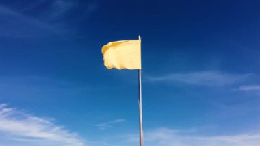 Mavi gökyüzünde dalgalanan küçük sarı bayrak