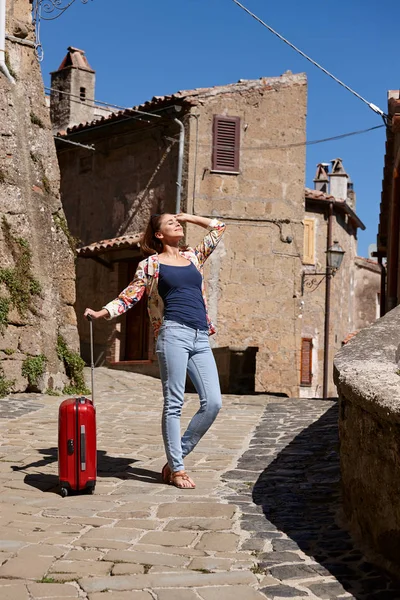 Молодая девушка с чемоданом. Концепция отпуска. Старый город в Тоскане — стоковое фото