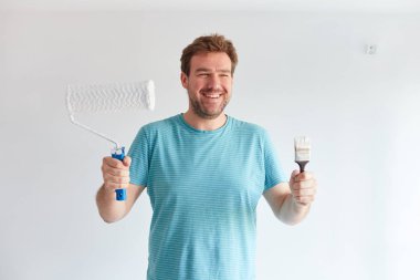 Gülümseyen adam bir fırça ve bir rulo önünde tutan