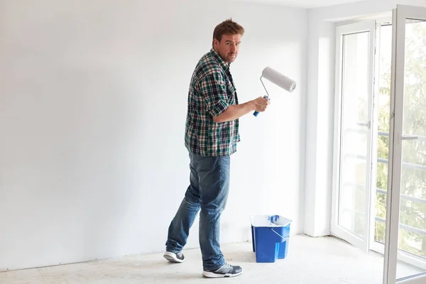 Young man painting a wall on white in a modern home