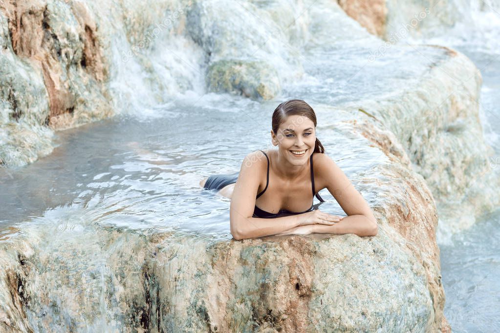 Pretty young brunette woman taking a bath in the natural thermal