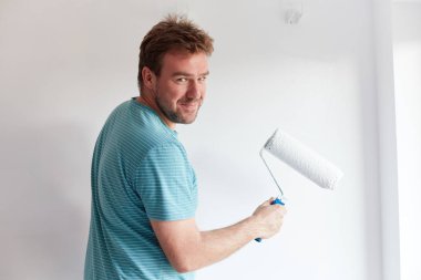 Genç adam bir modern ev beyaz bir duvar boyama