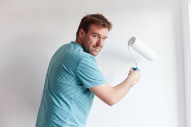 Genç adam bir modern ev beyaz bir duvar boyama