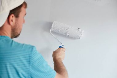 Genç adam bir modern ev beyaz bir duvar boyama