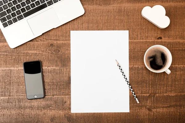 Office desk table. Top view with blank white paper, laptop, pencil and coffee  on wooden table background. Top view with copy space