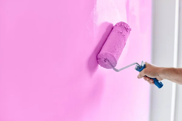 Maschio pittura a mano parete con rullo di vernice. Appartamento di pittura, ristrutturazione con vernice color lavanda — Foto Stock