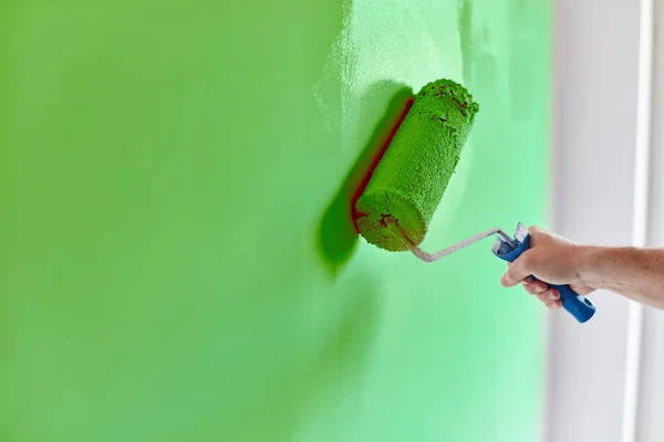 Mur de peinture à la main masculin avec rouleau de peinture. Peinture appartement, rénovation avec de la peinture de couleur verte — Photo