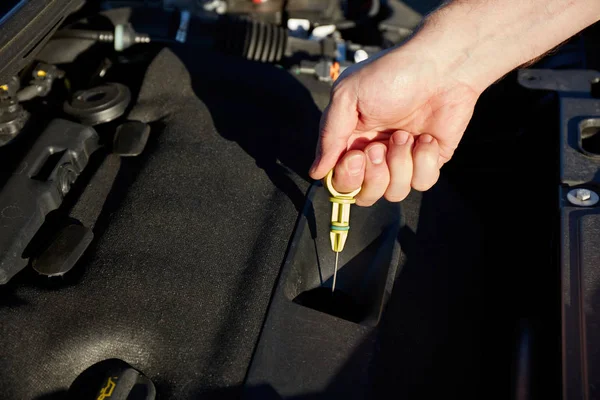 Mannenhand die de oliepeilstok vasthoudt - het oliepeil controleren — Stockfoto