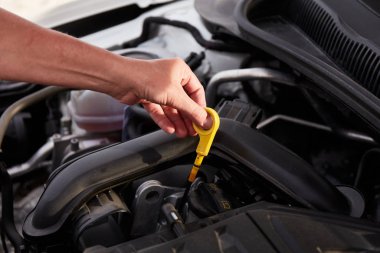 Motor yağını kontrol ediyorum. Yağ süngüsünü tutan bir kadın eli. 