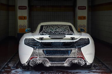 Oslo/Norway- 06.03.2016: Mclaren 650s in the washing cycle in an automatic car wash clipart