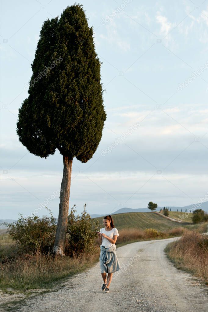 A young girl with a phone call on the road known from the movie Gladiator, near Pienza in Tuscany