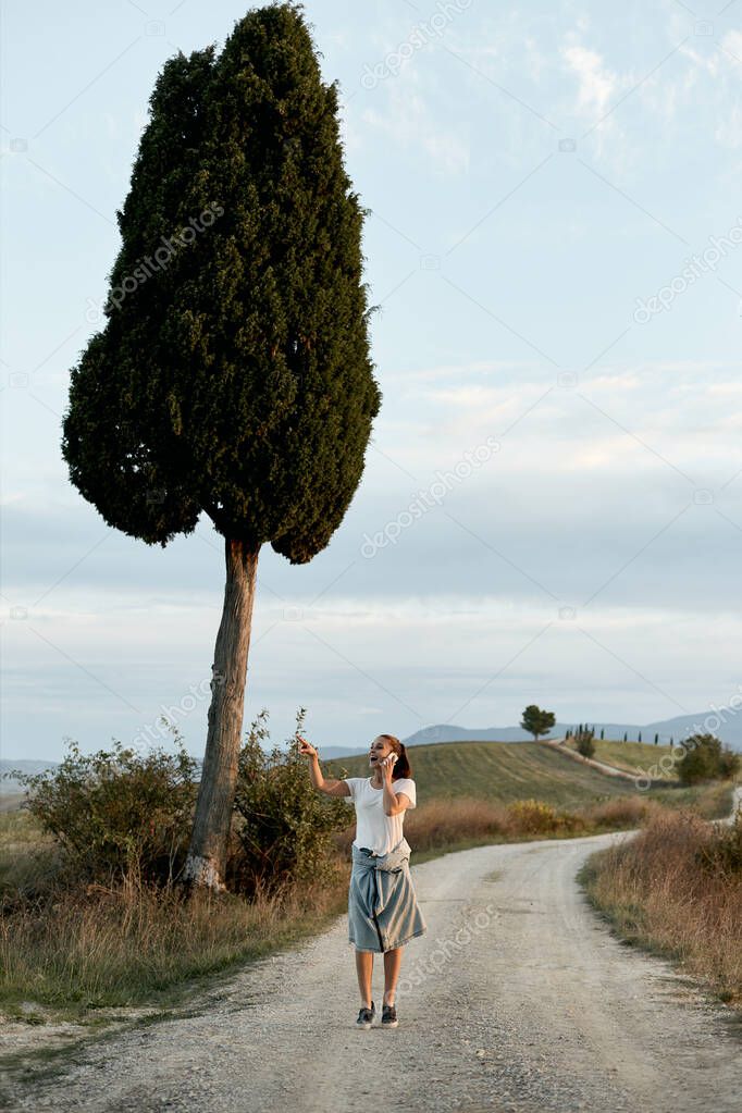 A young girl with a phone call on the road known from the movie Gladiator, near Pienza in Tuscany