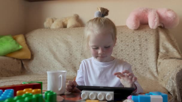 Kleine Blondine Spielt Tablet Und Isst — Stockvideo