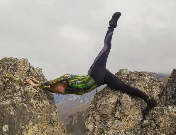 Junge Frau in Yogaposition auf den Felsen in den Bergen — Stockfoto
