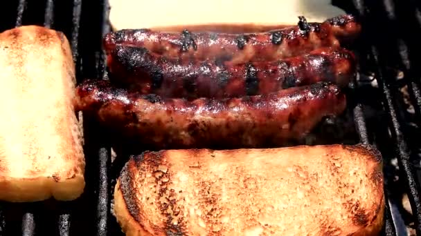 Baking fresh sausages and bread on grill — Stock Video
