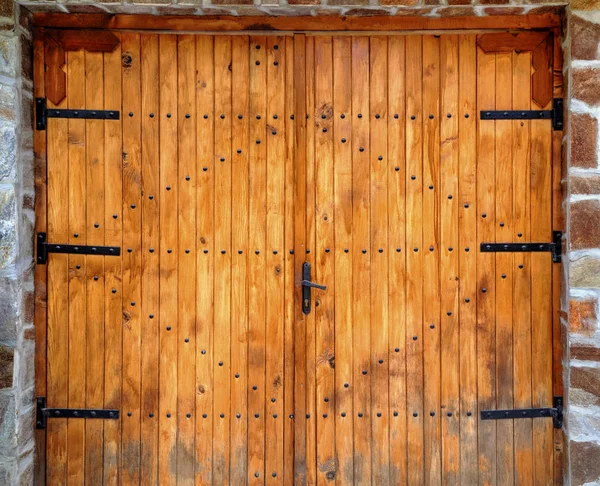 Porte en bois avec ornements métalliques sur mur de pierre — Photo