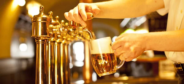 Gouden bier in de hand en bier kranen — Stockfoto