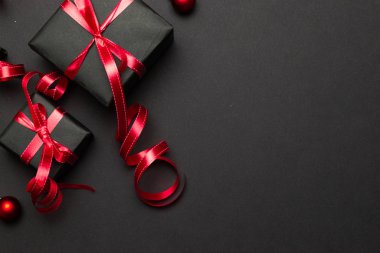 Kırmızı Noel hediyeleri, siyah arka plan manzaralı süsler. Kış tatili hediyesi. Mutlu Noeller ve mutlu bayramlar tebrik kartı, çerçeve, pankart. Yeni yıl. Noel. Düz yatıyordu