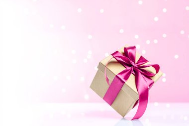Hediye kutusu kırmızı kurdele pembe arka planda izole edilmiş. Xmas hediyesi. Noel sürprizi. Bayram için şenlikli zemin Doğum günü, Sevgililer Günü