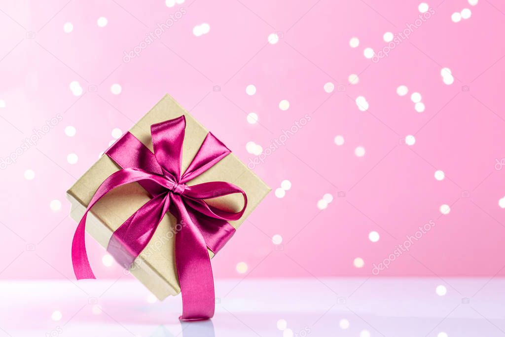 Christmas background. Pink Christmas decorations.Holiday festive celebration concept. Gift box red ribbon isolated on pink