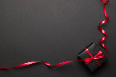 Yeni yıl geçmişi. Siyah arka planda kırmızı kurdeleli Noel hediyeleri. Xmas hediyesi. Kış tatili konsepti. Mutlu Noeller ve mutlu bayramlar tebrik kartı, çerçeve, bayrak
