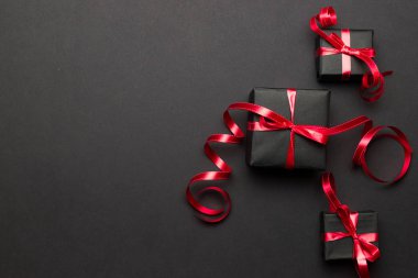 Hediye kutusu kurdelesi. Noel hediyeleri, siyah arka planda kırmızı dekor. Xmas hediyesi. Kış tatili konsepti. Yeni yıl. Noel..