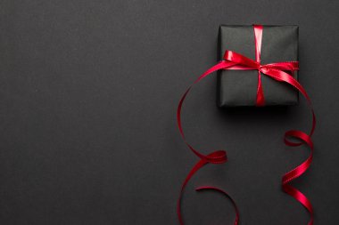 Yeni yıl geçmişi. Siyah arka planda kırmızı kurdeleli Noel hediyeleri. Xmas hediyesi. Kış tatili konsepti. Mutlu Noeller ve mutlu bayramlar tebrik kartı, çerçeve, bayrak