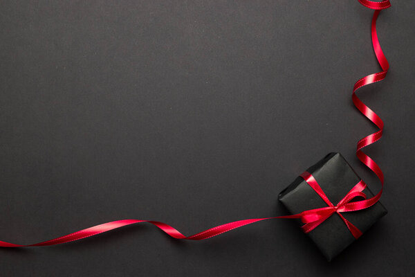 New years background. Christmas gifts with red ribbon on black background. Xmas present. Winter holiday concept. Merry Christmas and Happy Holidays greeting card, frame, banner