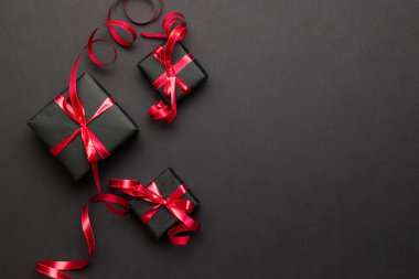 Hediye kutusu kurdelesi. Noel hediyeleri, siyah arka planda kırmızı dekor. Xmas hediyesi. Kış tatili konsepti. Yeni yıl. Noel..