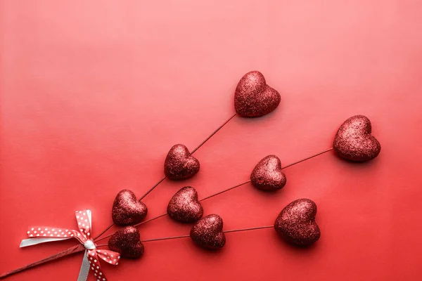 Fondo del día de San Valentín. Pequeños corazones rojos en palos sobre fondo rojo. Símbolo del amor . — Foto de Stock