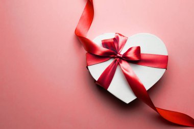 Valentines day background. White gift box with bow and red ribbon heart, photo template, background. Top View.