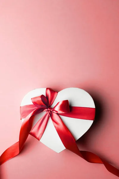 Banner del día de San Valentín. Caja de regalo en forma de corazón con cinta roja aislada en rojo. Plantilla de mensaje romántico con espacio de copia . — Foto de Stock