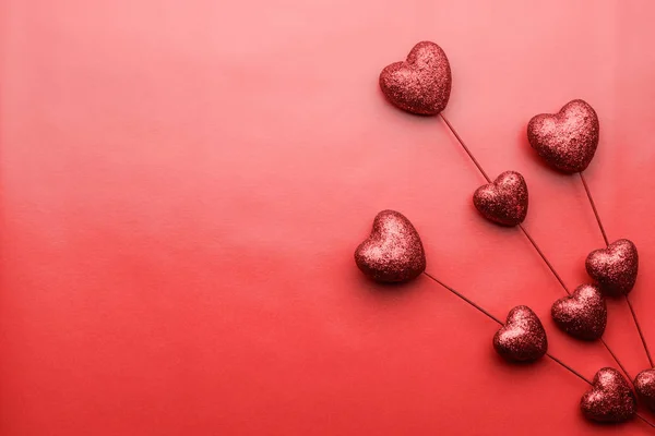Valentýn červené srdíčko na tyčinky na červeném pozadí. Symbol lásky. — Stock fotografie